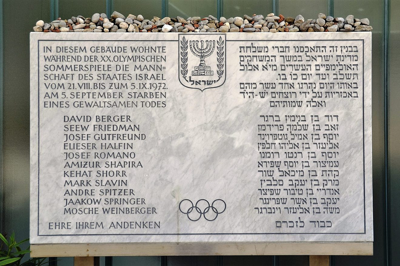 A plaque in front of the Israeli athletes' quarters commemorates the victims of the 1972 Munich Olympics massacre. The inscription, in German and Hebrew, reads: “The team of the State of Israel lived in this building during the 20th Olympic Summer Games from 21 August to 5 September 1972. On 5 September, [list of victims] died a violent death. Honor to their memory.” Credit: Wikimedia Commons.