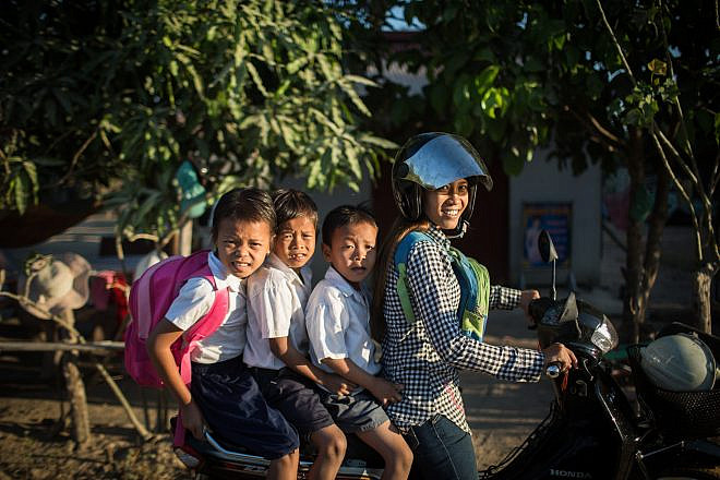A Cambodian woman takes her kids to school on a motorbike in a small village at the Angkor Wat temple complex, in Siem Reap, Cambodia, on Feb. 26, 2016. Photo by Hadas Parush/Flash90.
