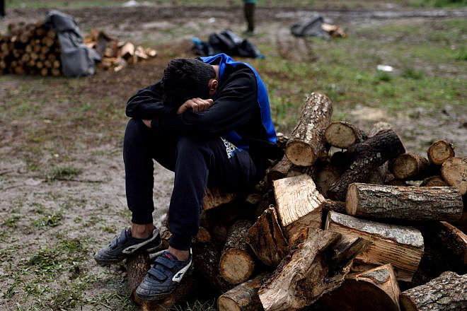 A young Syrian refugee takes a rest at a firewood distribution point at Idomeni refugee camp on May 3, 2016. Photo: Gili Yaari/Flash90