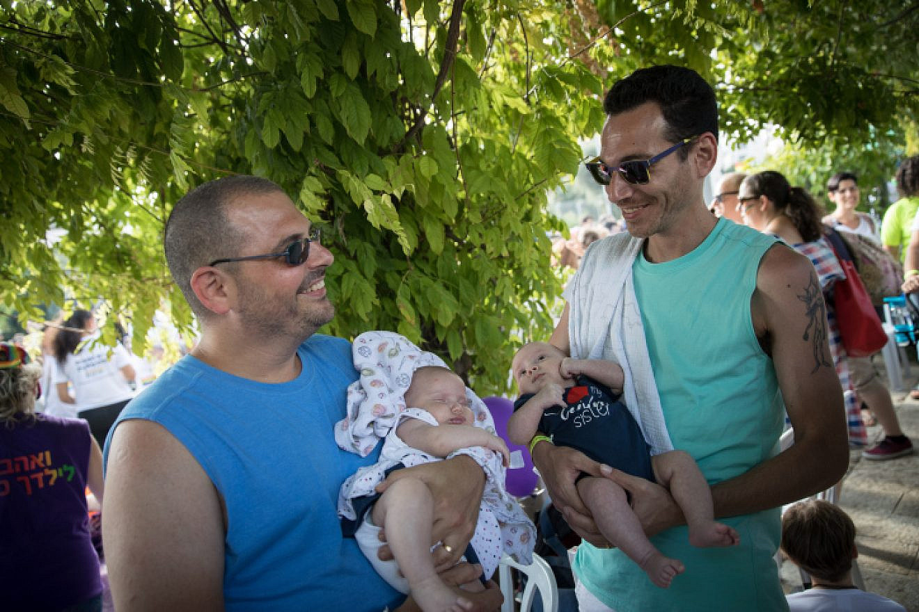 A couple holds their children, conceived through a surrogate mother, during the Pride Parade in Jerusalem, Thursday, Aug. 2, 2018. Photo By Hadas Parush/Flash90.