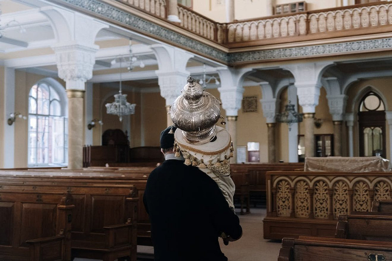 A Jewish man holds a Torah in synagogue. Credit: Cottonbro Studio/Pexels.