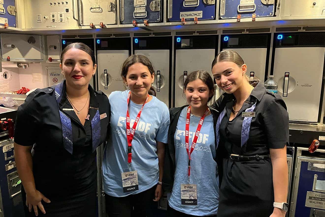 Two of the campers with El Al flight attendants, who also went on the summer-camp program when they were teens, during the flight from Israel to the United States, July 2023. Photo by Ori Shemesh/FIDF.