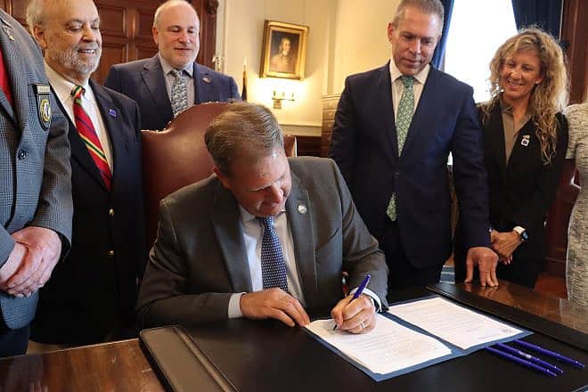 New Hampshire Gov. Christopher Sununu signs an executive order against the anti-Israel BDS movement as to his left, Israeli Ambassador to the United Nations Gilad Erdan looks on, July 6, 2023. Credit: Israeli-American Coalition for Action.