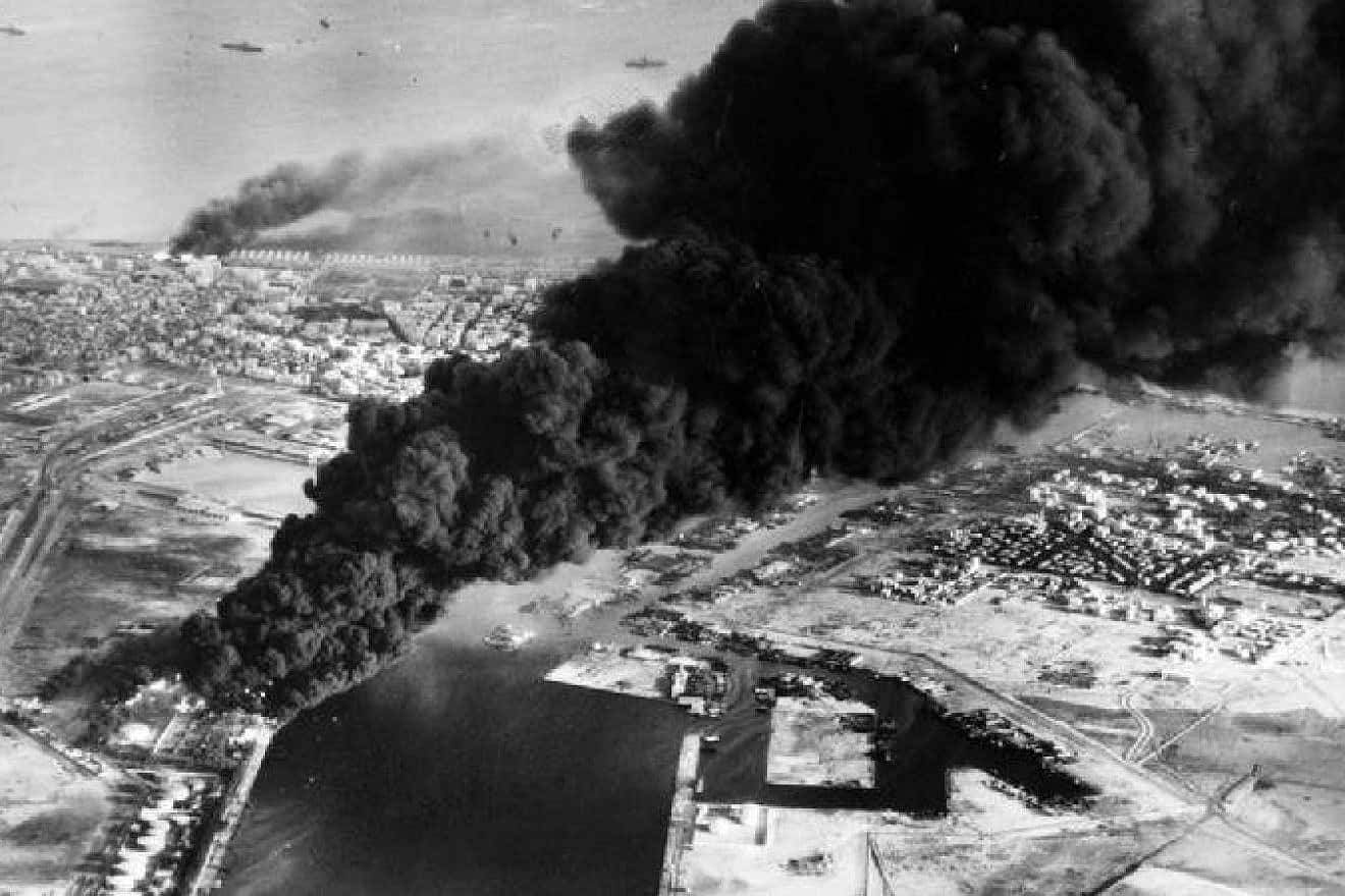 Smoke rises from oil tanks beside the Suez Canal hit during the initial Anglo-French assault on Port Said, Egypt, in November 1956. Credit: Wikimedia Commons.