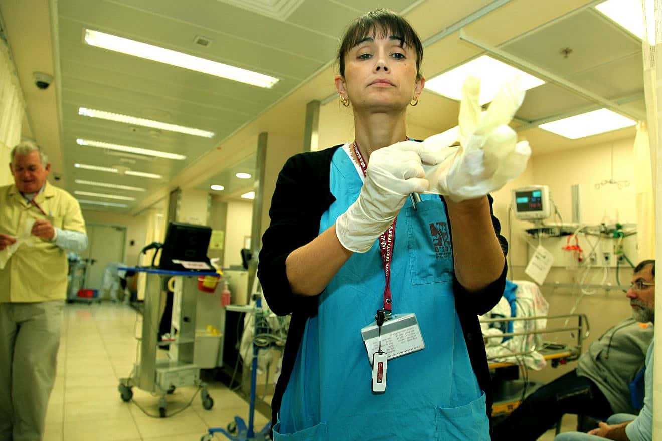 A nurse dons gloves before treating a patient at Rambam Medical Center in Haifa. Jan. 30, 2011. Photo by Moshe Shai/Flash90.