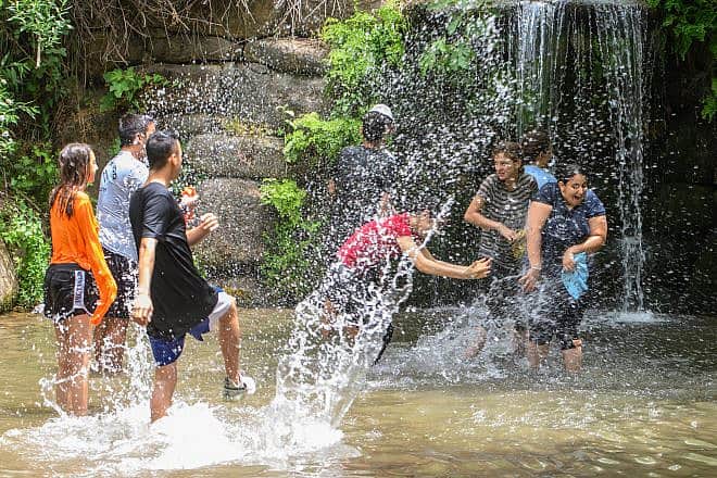 People play in the springs and waterfalls of the Snir Stream, one of the tributaries to the Jordan River. in northern Israel, May 22, 2023. Photo by Ayal Margolin/Flash90.