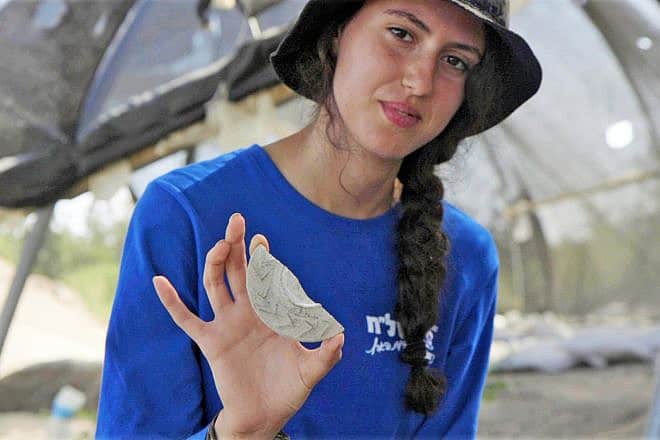 Youth leader Aviv Weizman holds the "magical mirror" plaque she discovered at Usha. Photo by Emil Aladjem/Israel Antiquities Authority.