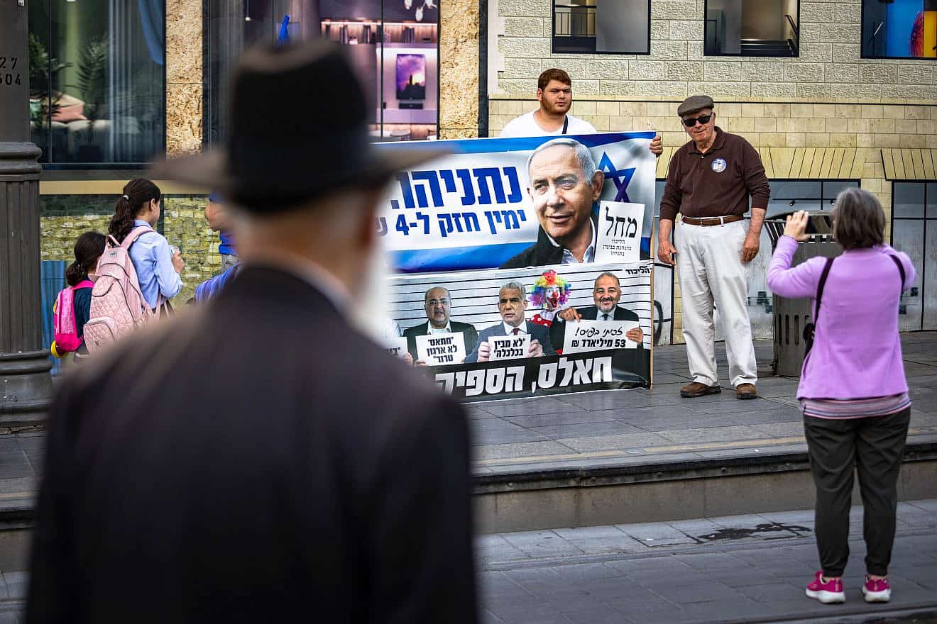 Israelis walk past posters for the November elections in Jerusalem, with some stopping to take a photo, on Oct. 24, 2022. Photo by Olivier Fitoussi/Flash90.