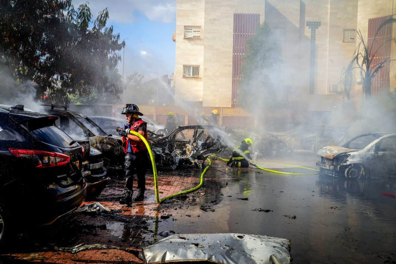 Firefighters tackle burning cars set aflame by a rocket launched from the Gaza Strip that landed in the southern Israeli city of Beersheva on Oct. 7, 2023. Photo by Dudu Greenspan/Flash90.