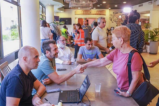 From left: Yossi Biton from Kfar Aza, Guy Lerer from Hazinor, Mendi Blau of Colel Chabad and Gadi Teichman Dan from the International Fellowship of Christians and Jews distribute debit cards to the residents of Kfar Aza, who lost everything and are now living in hotels. Photo by Raanan Cohen.