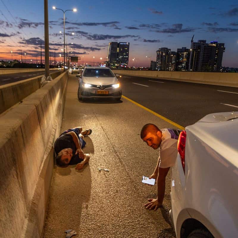 Israelis take cover by the side of a highway as a siren warns of incoming rockets, Oct. 17, 2023. Photo by Yossi Aloni/Flash90.