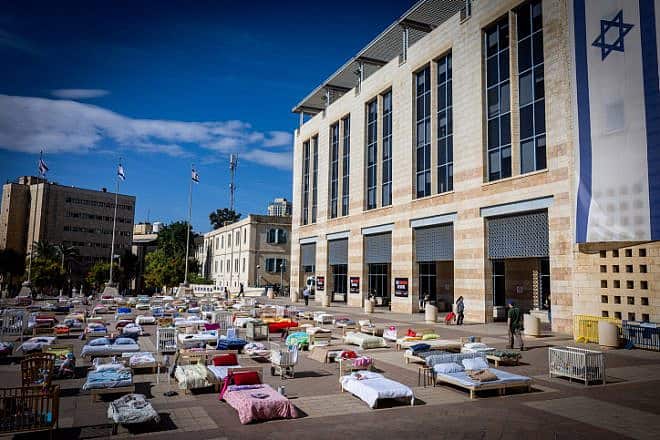 People walk between hundreds of beds, each symbolizing a captive held by Hamas in the Gaza Strip, outside Jerusalem City Hall, Oct. 30, 2023. Photo by Yonatan Sindel/Flash90.