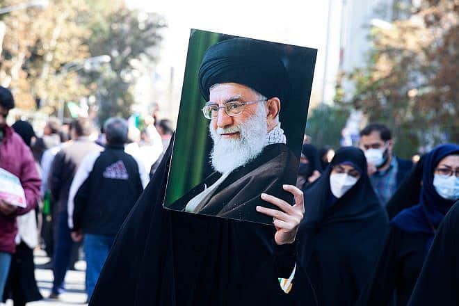 A veiled woman holds a photo of Iran's Supreme Leader Ayatollah Ali Khamenei on Nov. 4, 2022. Credit: saeediex/Shutterstock.