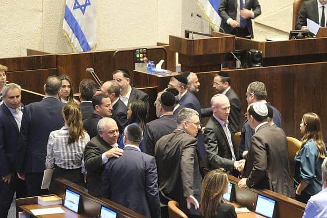Lawmakers in Jerusalem congratulate one another after Israel's unity government is sworn in, Oct. 12, 2023. Credit: TPS.