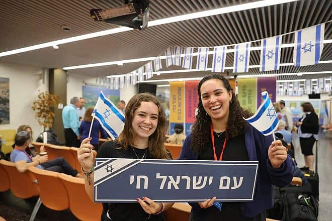 New immigrants to Israel hold a placard at Ben-Gurion International Airport reading, “The People of Israel Live,” Oct. 19, 2023. Photo by Yonit Schiller.