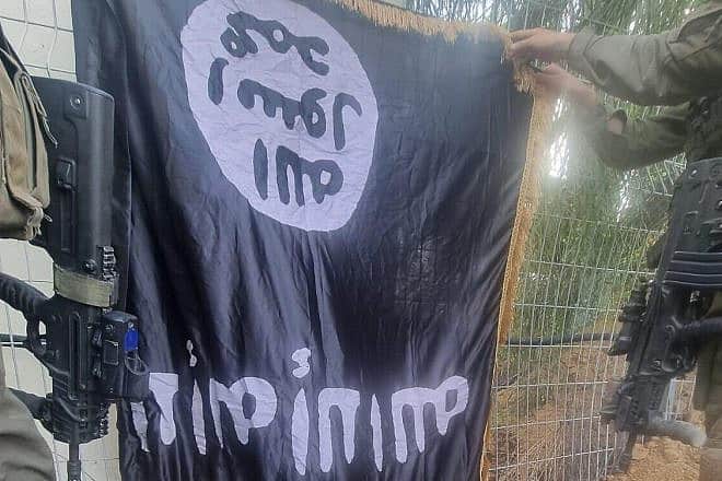 Israeli soldiers hold an ISIS flag found on the body of a Hamas terrorist at Kibbutz Sufa on Oct. 12. Credit: IDF Spokesperson.