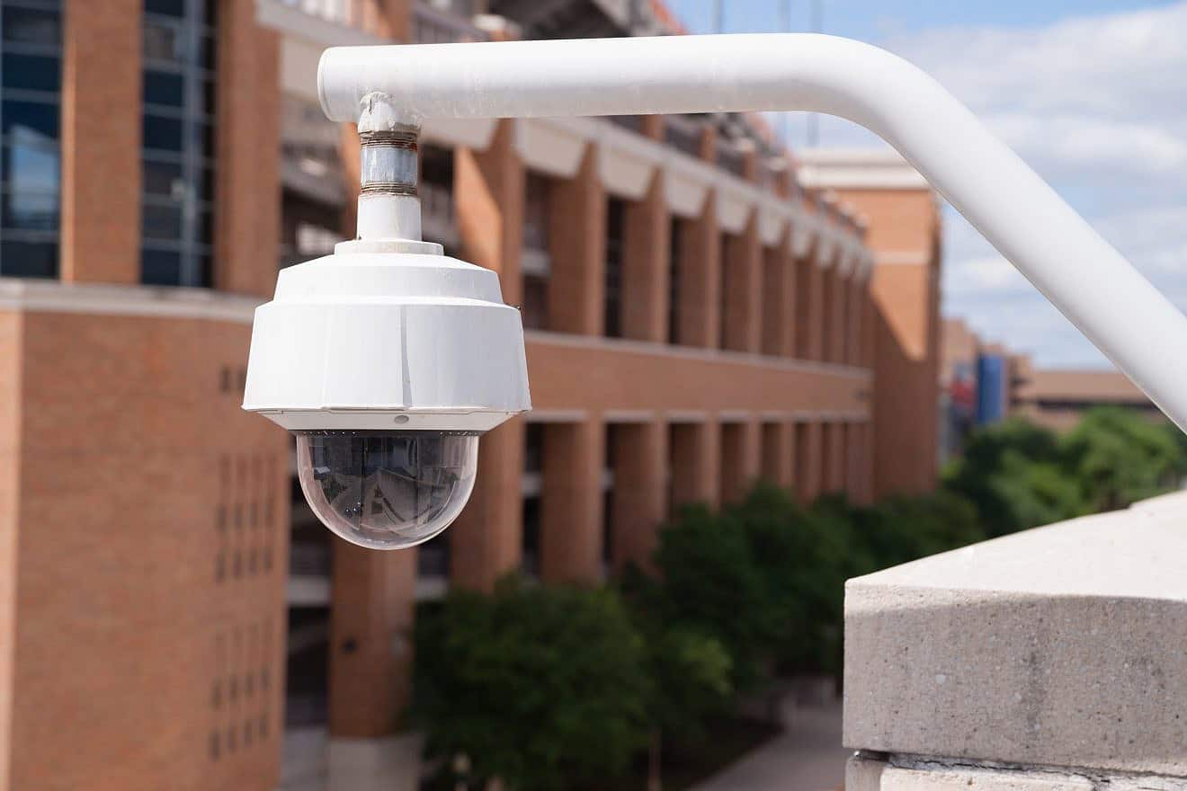 A video security camera mounted high on a college campus. Credit: Real Window Creative/Shutterstock.