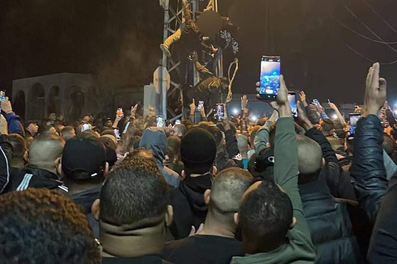 A crowd cheers as the corpses of two men accused of collaborating with Israel are hung on an electrical tower in Tulkarem, Nov. 25, 2022. Source: X.