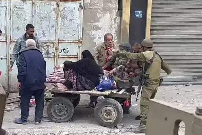 Israeli soldiers help an elderly Gazan woman, November 2023.