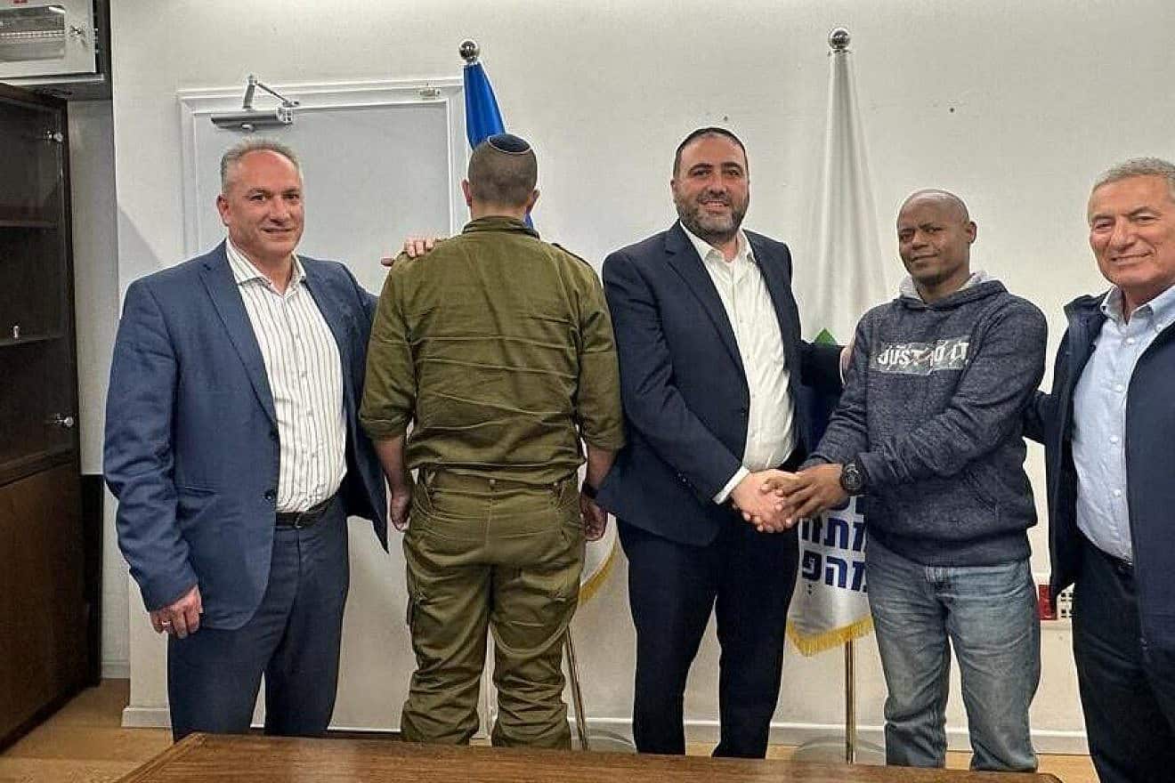 Mulugeta Tsagi shakes hands with Interior Minister Moshe Arbel as Lt. Col. "Yud," whose life Tsagi saved in Sderot on Oct. 7, faces away from the camera, Nov. 26, 2023. Credit: Interior Ministry.