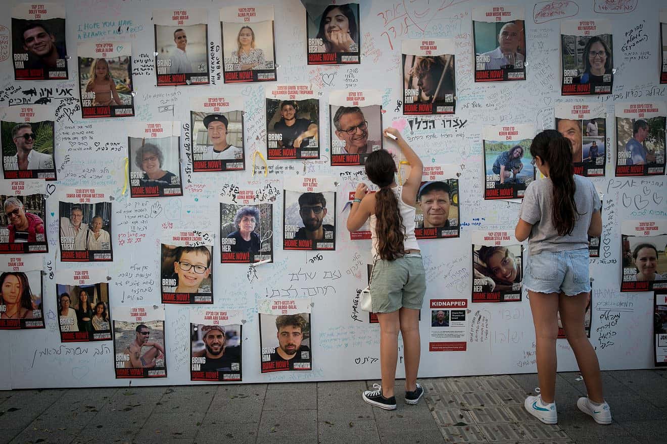 Girls write a message on posters showing  photos of Israelis held kidnapped by Hamas terrorists in Gaza outside the Tel Aviv Museum of Art on Oct. 28, 2023. Photo by Miriam Alster/Flash90.