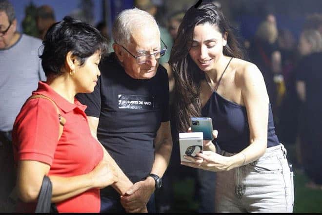 Shani Bibi shows two deaf Israelis how to use a smart watch to learn about rocket alerts. Photo: Shlomi Yosef.