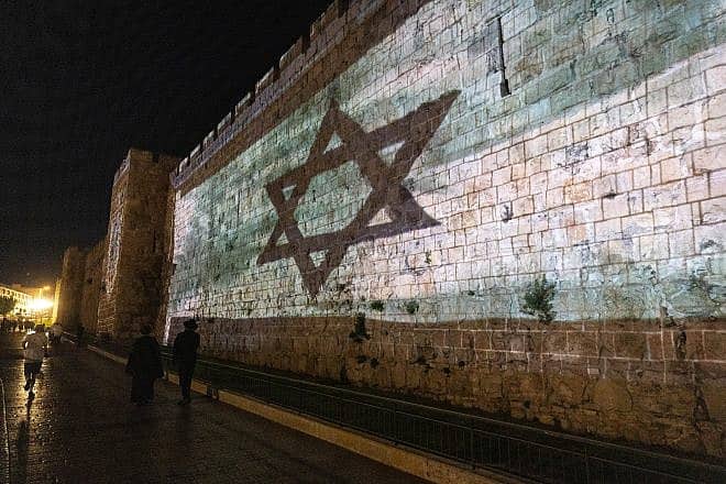 The Israeli flag is screened on the walls of Jerusalem's Old City on Nov. 7, 2023, exactly one month after the murderous attacks on southern Israel perpetrated by Hamas terrorists on Oct. 7. Photo by Chaim Goldberg/Flash90.