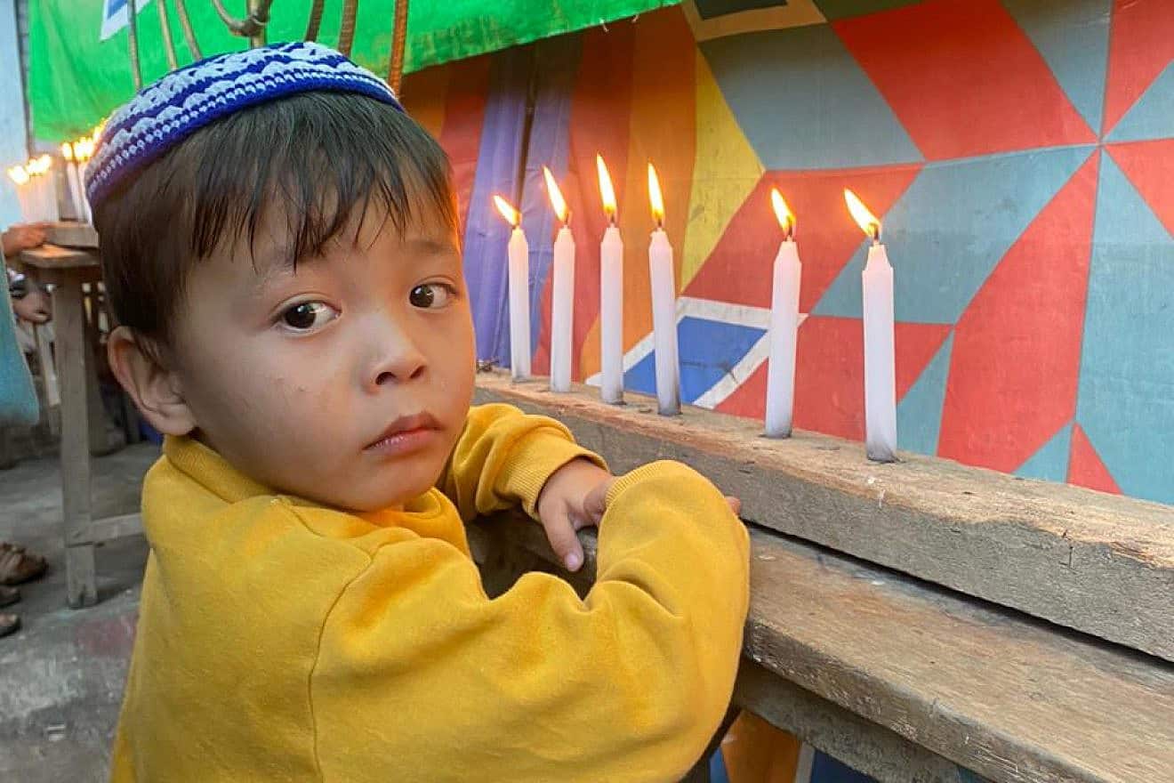 Ezra Janggousang, 3, lights candles with his family and community on the first night of Chanukah in Churachandpur, India, on Dec. 7, 2023. Credit: Courtesy of Shavei Israel.