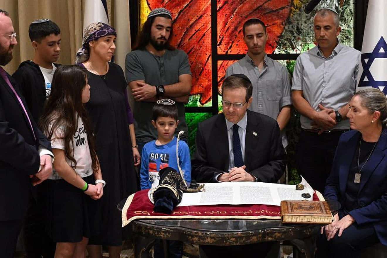 President Isaac Herzog writes a letter in a Torah scroll in honor of the victims of Kibbutz Be'eri, Dec. 3, 2023. Photo by Haim Zach/GPO.