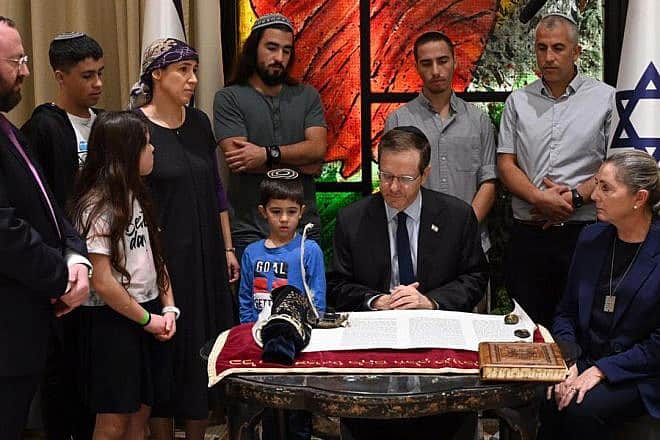 President Isaac Herzog writes a letter in a Torah scroll in honor of the victims of Kibbutz Be'eri, Dec. 3, 2023. Photo by Haim Zach/GPO.