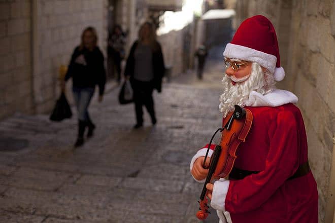People walk next to a Santa Claus doll for Christmas in a shop in Jerusalem's Old City in December 2015.  Photo by Lior Mizrahi/Flash90.