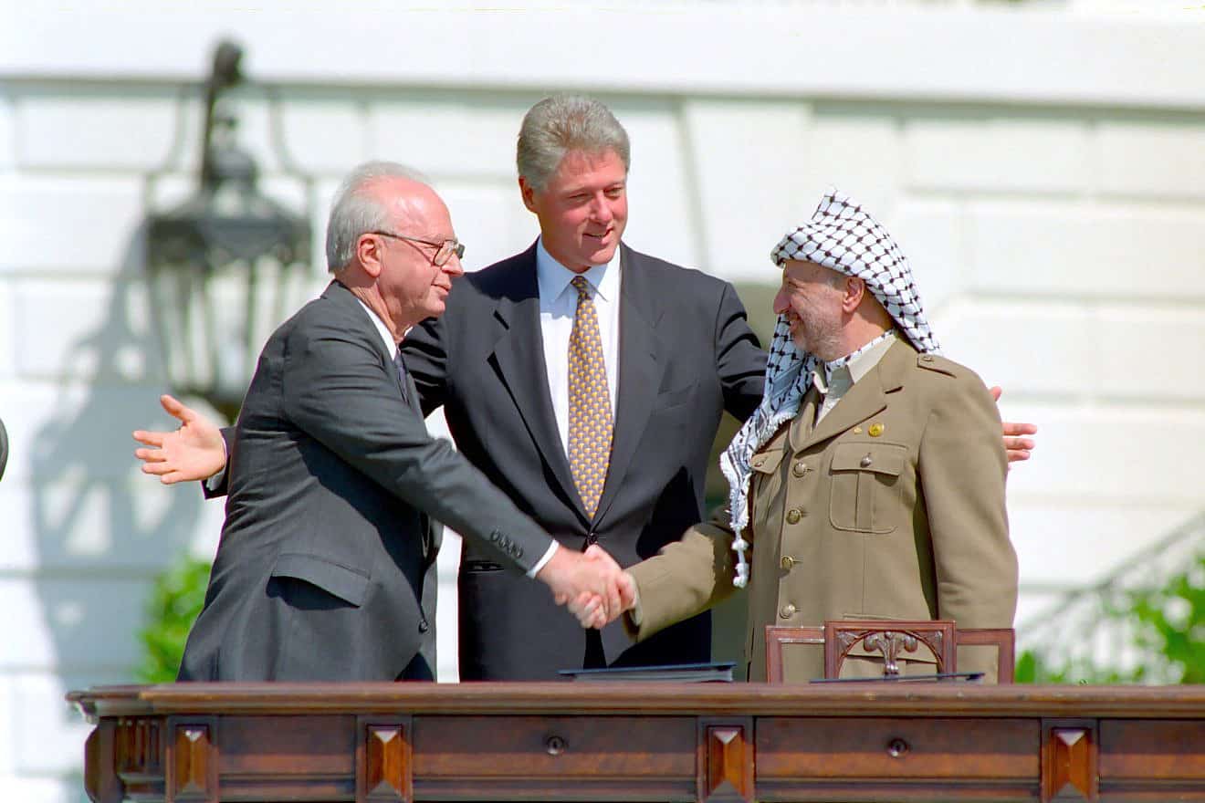 U.S. President Bill Clinton looks on as Israeli Prime Minister Yitzhak Rabin and Palestine Liberation Organization head Yasser Arafat shake hands at the signing of the Oslo Accords on Sept. 13, 1993. Credit: William J. Clinton Presidential Library/National Archives & Records Administration.