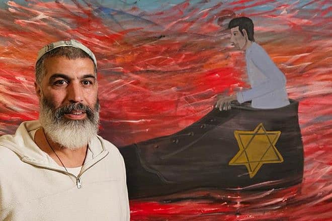 Israeli artist Shai Azoulay next to one of his works from the "Bigger Than Me" exhibition. Credit: Yad Vashem.