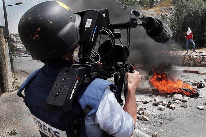 A photojounalist records a video of Palestinian rioters. Photo: Ruben Salvadori / Flash 90