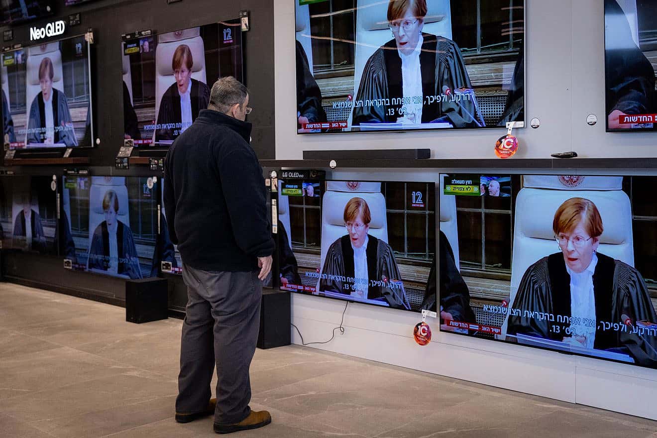 A man looks at television screens that are broadcasting a court hearing from the International Court of Justice in the law suit of South Africa against Israel, at a shop in Jerusalem on Jan. 26, 2024. Photo by Chaim Goldberg/Flash90.
