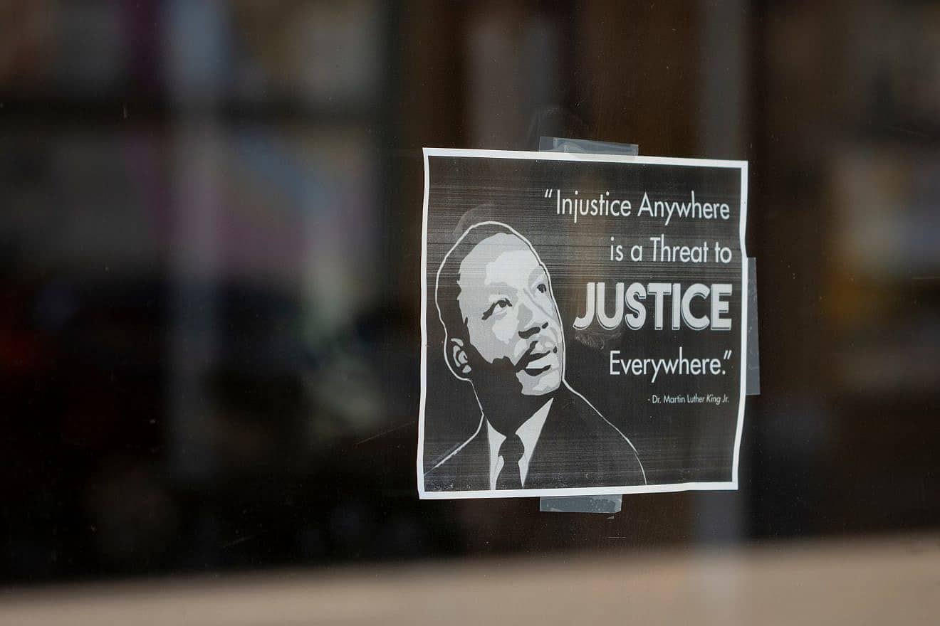 A printed sign that promotes social justice by quoting a motto from Martin Luther King Jr., seen on a storefront window in Portland, Ore., on July 4, 2021. Credit: Tada Images/Shutterstock.