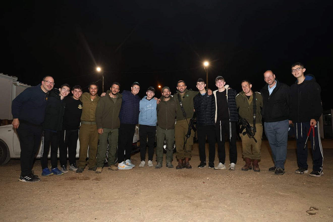 Gathered at a Tzur Hadassah army base are (from left) TABC associate principal Rabbi Steven Finkelstein, TABC students, Israeli soldiers and director of OU Relief Missions Rabbi Ethan Katz (second from right). Credit: Courtesy.