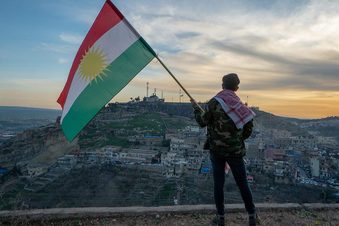 Teenager holding the Kurdistan flag in northern Iraq at sunset time on Nowruz 2019. Credit: Felix Friebe/Shutterstock.