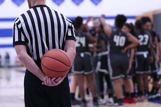 A basketball referee holds a ball during a timeout, in a stock photo. Credit: Ron Alvey/Shutterstock.