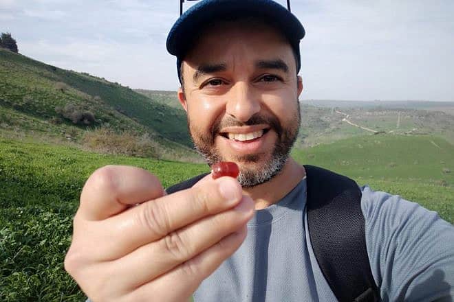 Erez Abrahamov holds an ancient Assyrian amulet he found in the Nahal Tabor Nature Reserve. Photo by Erez Abrahamov.