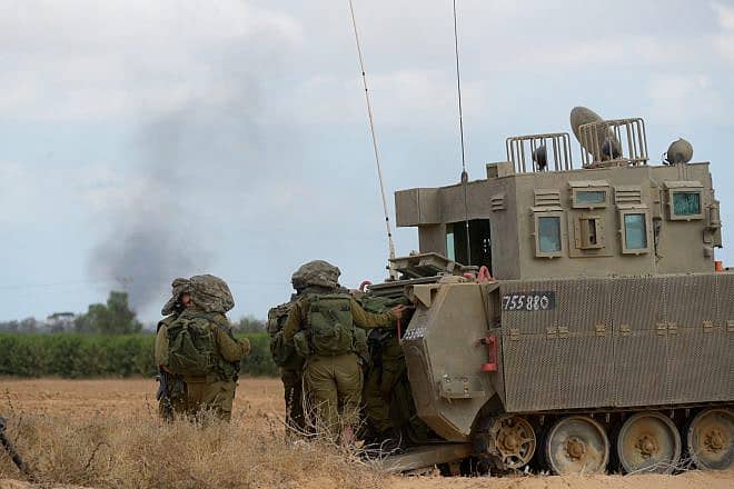 Israeli soldiers and armored vehicles are seen as smoke rises in the background near Kibbutz Sufa on the Gaza border, July 17, 2014. Photo by Gili Yaari/Flash90.