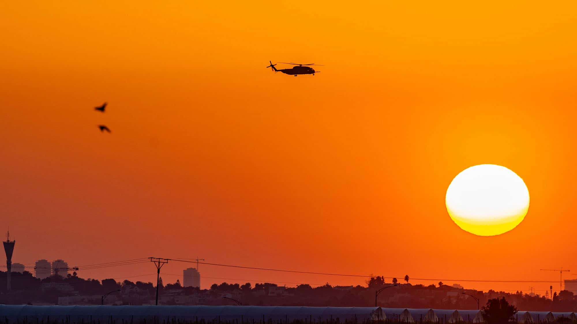 A military helicopter flies at sunset near the Israeli border with the Gaza Strip, March 11, 2024. Photo by Chaim Goldberg/Flash90.